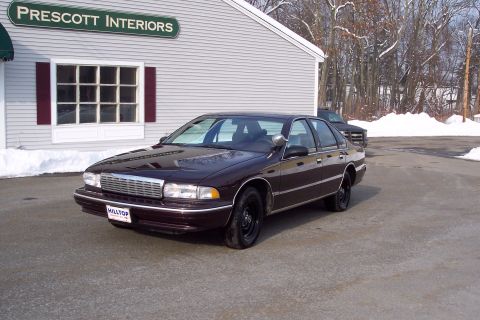 2001 Ford Crown Victoria - A dark sedan, likely a 1996 Chevrolet Caprice, is parked outside Prescott Interiors on a snowy day.