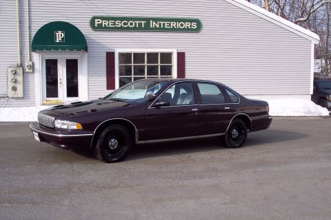 2001 Ford Crown Victoria - A dark sedan is parked outside the Prescott Interiors building on a snowy day.