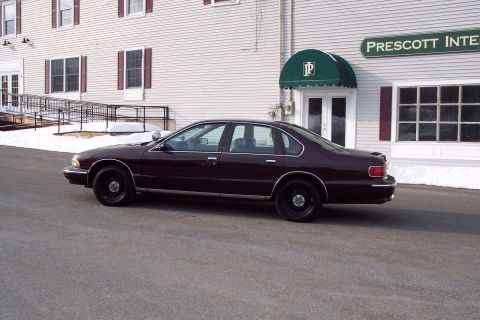 2001 Ford Crown Victoria - A maroon sedan is parked in front of a building with a sign that reads 'PRESCOTT INTE'.