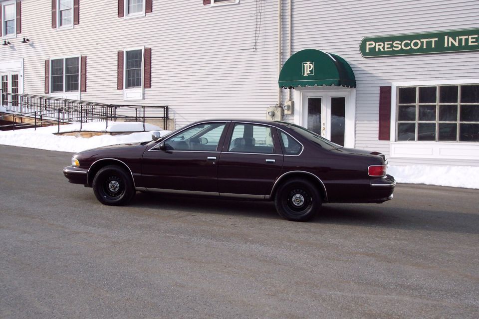 maroon sedan parked outside a building with a green awning