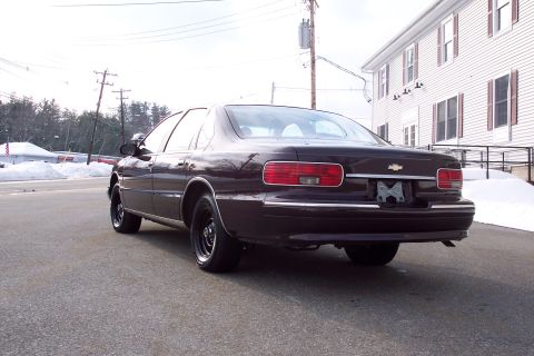 2001 Ford Crown Victoria - Rear view of a dark-colored sedan with black steel wheels and chrome trim.