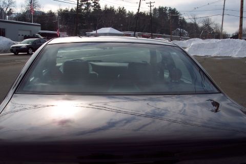 2001 Ford Crown Victoria - A dark sedan is parked in a lot with snow on the ground and trees in the distance.
