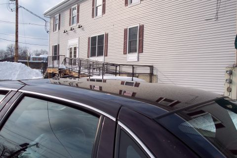 2001 Ford Crown Victoria - The reflection on the car's roof shows a building with a ramp and snow outside.