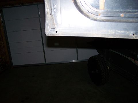 1988 Suzuki Samurai - A close-up view of a vehicle's door frame and a tire, with a garage door visible in the background.