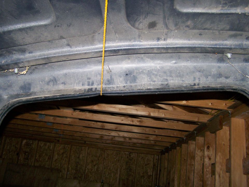 Interior view of a vehicle's hardtop roof with a yellow rope hanging down. Wood paneling and beams are visible below