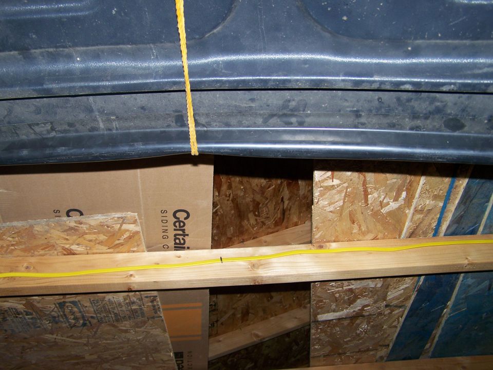 View inside a structure showing wood framing, cardboard boxes, and yellow wiring