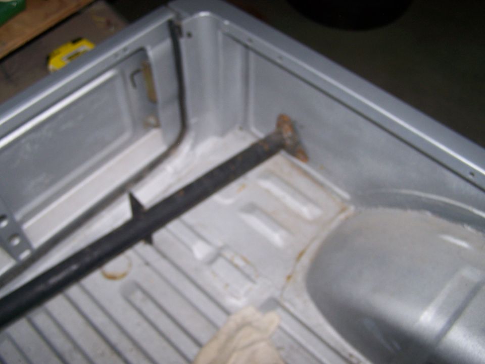 Silver truck bed interior with black bar and rust spots