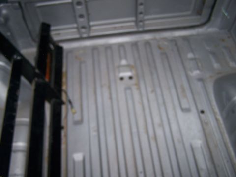 1988 Suzuki Samurai - The ribbed metal floor of a truck bed is visible, with some structural elements on the left side.