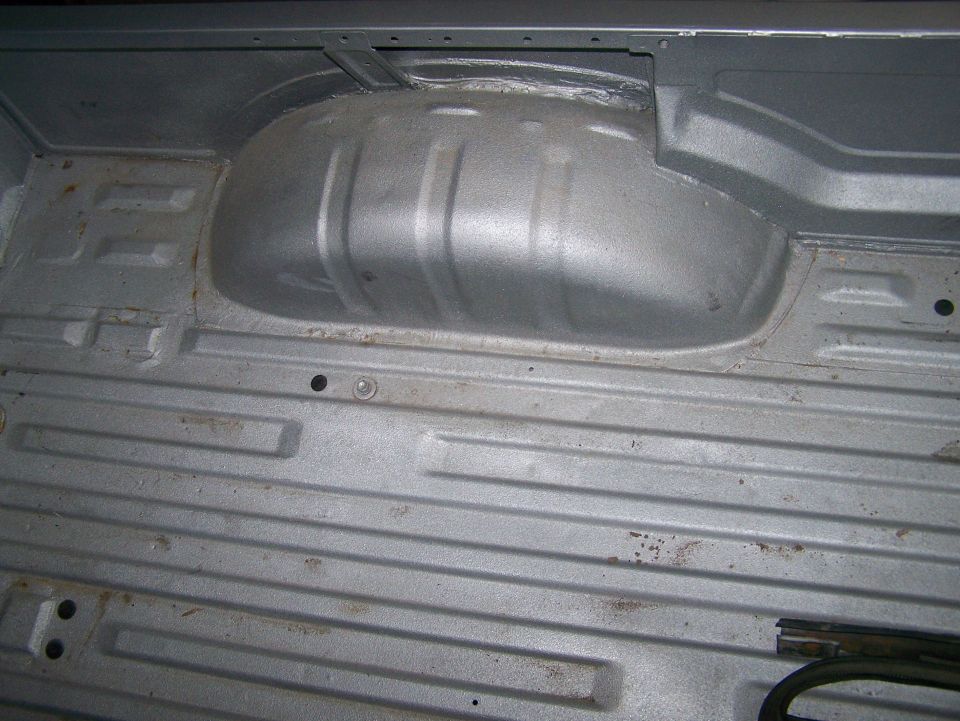 Underside of a vehicle's cargo bed, showing the wheel well and ribbed floor