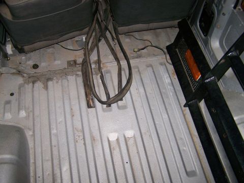 1988 Suzuki Samurai - The interior cargo area shows a ribbed floor and a black roll bar, with a hint of the rear seats visible.