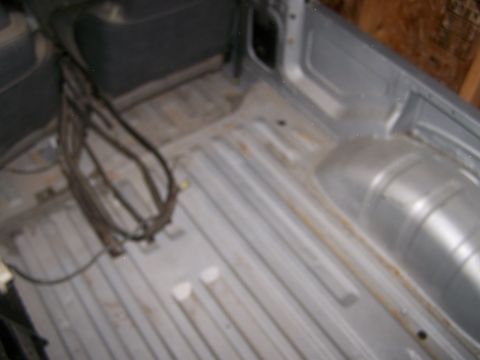 1988 Suzuki Samurai - Vehicle bed interior showing floor and wheel well area. Supermotors logo is present.