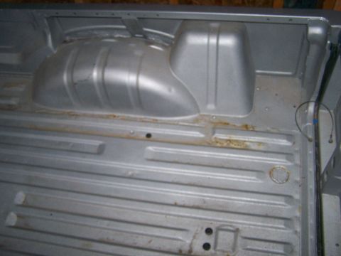 1988 Suzuki Samurai - The interior of a vehicle's cargo area shows a ribbed floor and a wheel well.