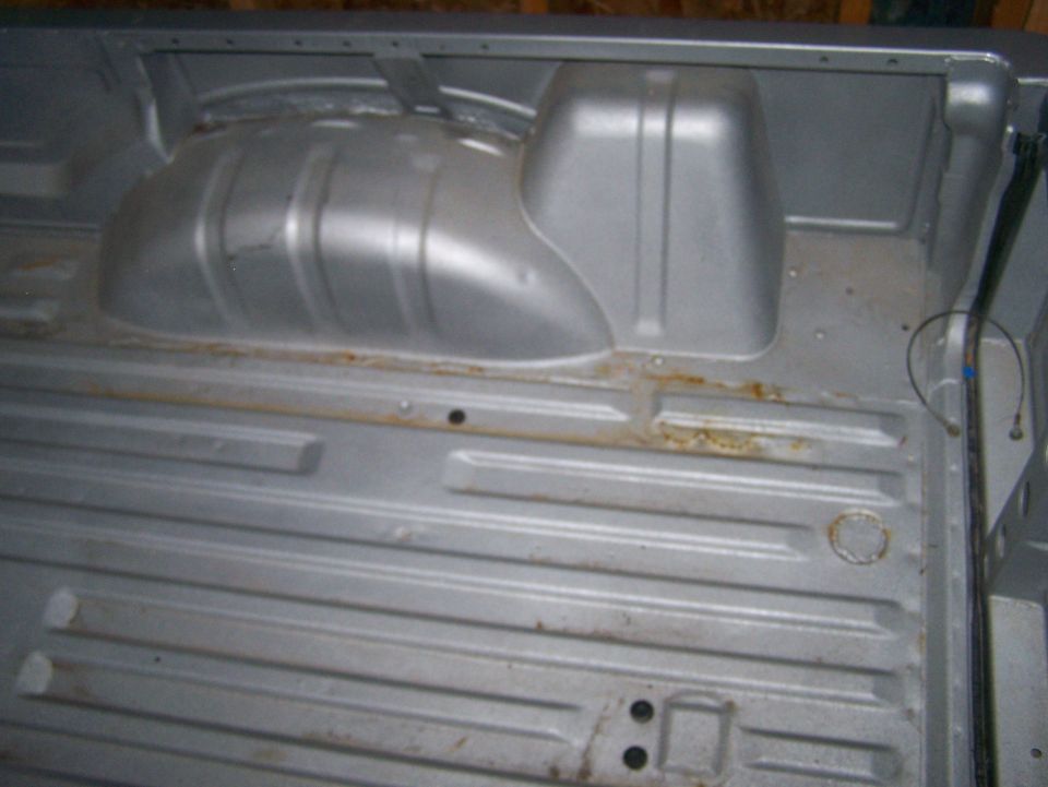 Interior of a vehicle bed, showing ribbed floor and wheel well