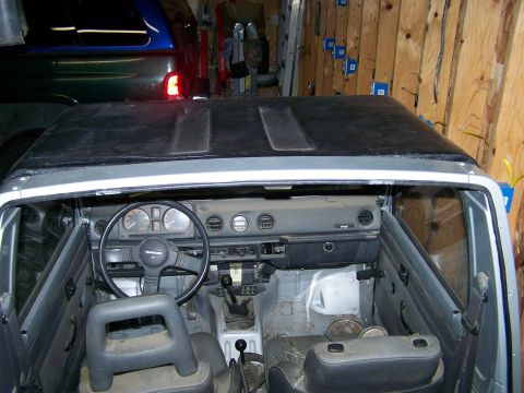1988 Suzuki Samurai - The interior of a Suzuki Samurai, showing the dashboard and seats, with another vehicle in the background.