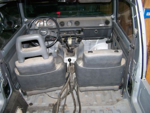 1988 Suzuki Samurai - The interior of a Suzuki Samurai, its dashboard, steering wheel, seats, and manual transmission shifter.