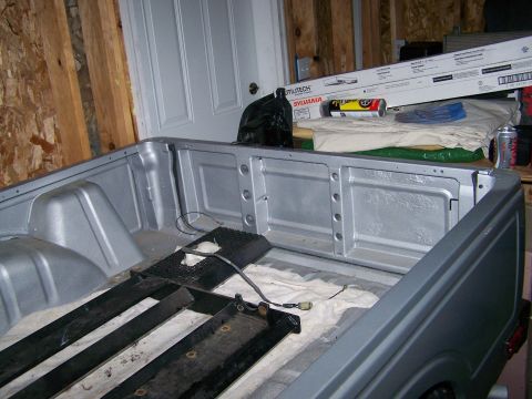 1988 Suzuki Samurai - The interior of a pickup truck bed, showing its silver-painted walls and floor, with some items stored inside.