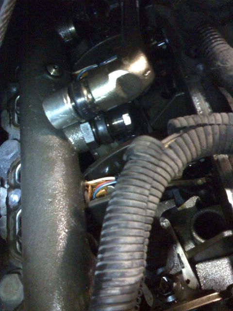 1992 Ford Bronco - Close-up view of engine components, including hoses and wiring, in a dark setting.
