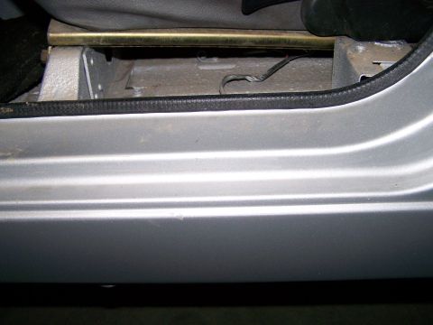 1988 Suzuki Samurai - Close-up view of the interior door sill and seat mounting hardware of a silver vehicle.