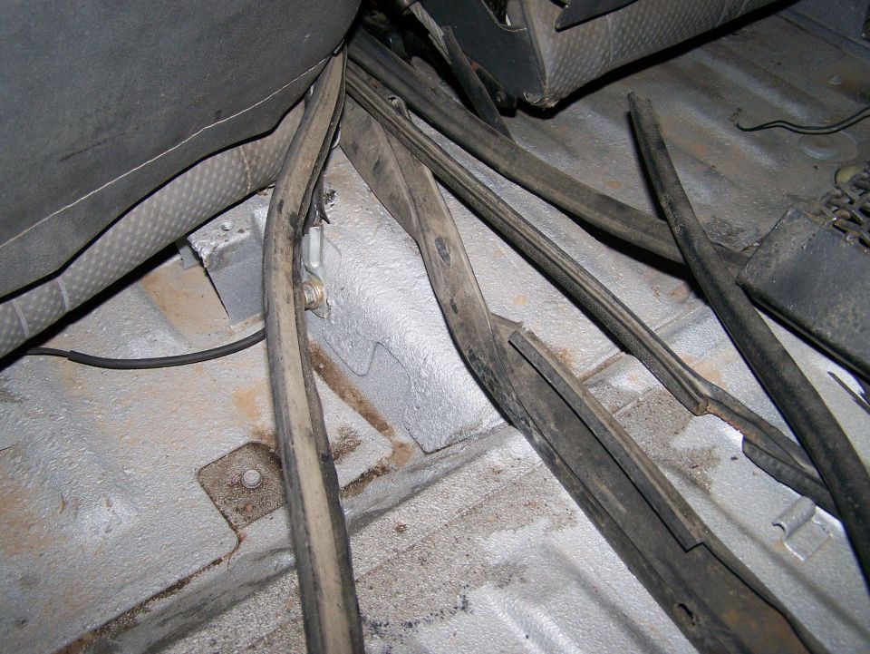 Interior floor of a vehicle with rubber seals and wiring visible