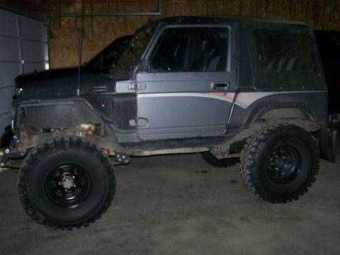 1988 Suzuki Samurai - This Suzuki Samurai is parked indoors, showing its lifted suspension and off-road tires.
