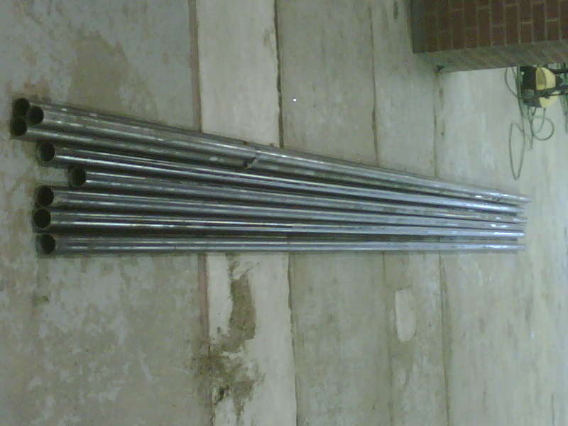 Stack of metal tubes leaning against a concrete wall