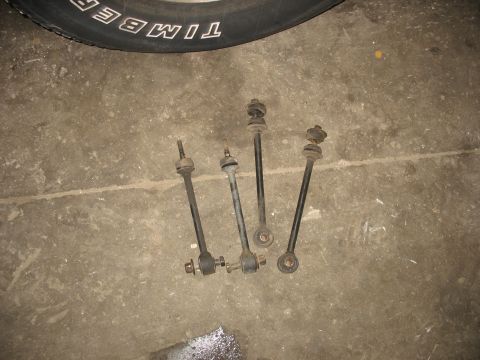 1995 Ford C-350 (Centurion Conversions) - Four sway bar end links are laid out on a concrete surface, with the tread of a tire visible in the upper portion of the image.