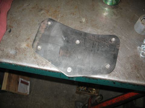 1995 Ford C-350 (Centurion Conversions) - Metal bracket with bolt holes sits on a workbench next to some hardware.