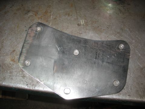 1995 Ford C-350 (Centurion Conversions) - A metal bracket sits on a workbench, showing signs of wear and modification.