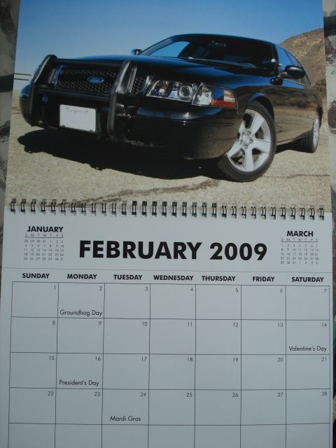 2000 Ford Crown Victoria - A black 2000 Ford Crown Victoria with a push bar is shown in a front 3/4 view on a calendar page for February 2009.