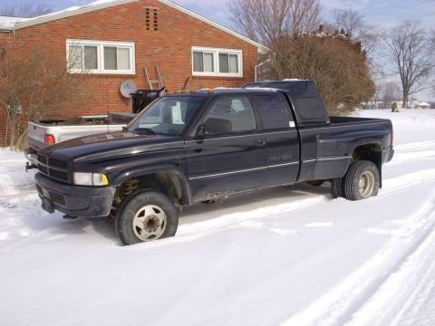 1995 Dodge 3500 - A black 1995 Dodge 3500 pickup truck is stuck in the snow with dual rear wheels visible.