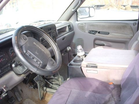 1995 Dodge 3500 - The interior of a Dodge pickup truck, the steering wheel, dashboard, and center console with a bottle in the cup holder.