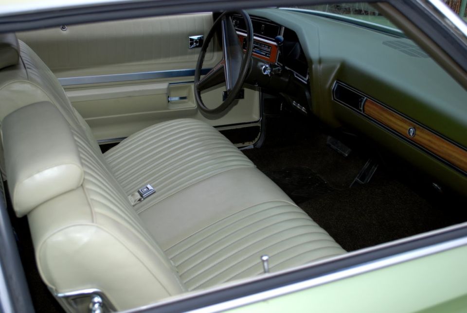 Cream vinyl bench seat interior of a 1970s Buick with woodgrain dash trim