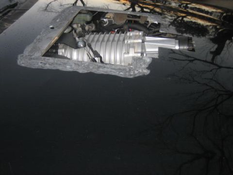 1996 Ford Thunderbird - Supercharger unit installed in cutout on black car hood.