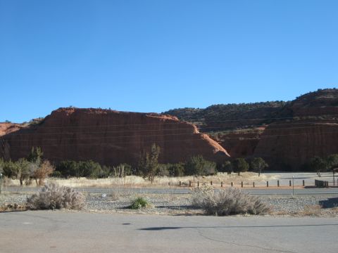 1993 Ford Bronco - A vast desert landscape unfolds under a bright blue sky, with prominent red rock formations dominating the horizon.