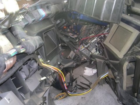 2007 Ford Mustang - The interior of a vehicle is shown with the dashboard removed, revealing complex wiring and internal components.