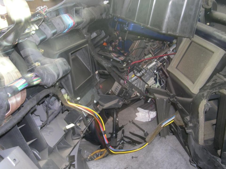 Car dashboard disassembled, showing wires, vents, and HVAC components