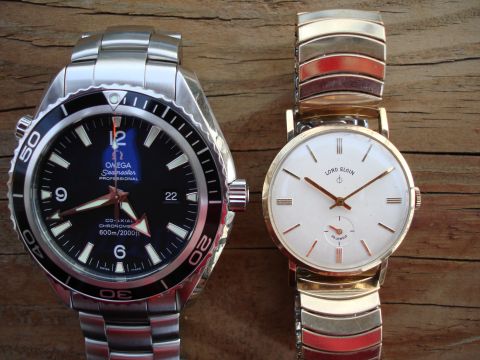 1994 Ford Bronco - A silver Omega Seamaster Professional and a gold-toned Lord Elgin watch are displayed side-by-side on a wooden background.