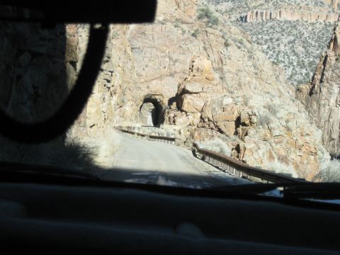 1993 Ford Bronco - The view from inside a vehicle shows a narrow road leading to a tunnel carved into a rocky mountainside.