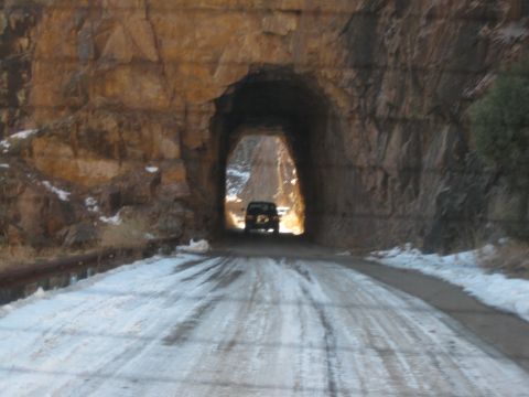 1993 Ford Bronco - A dark SUV drives through a tunnel on a snowy road, with snow visible on the surrounding rocks.