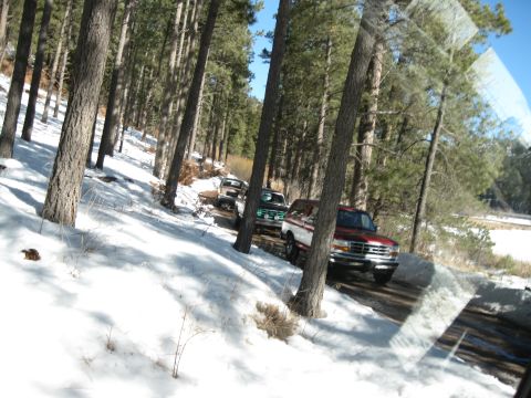 1993 Ford Bronco - Multiple Ford Broncos drive down a snow-covered forest road.
