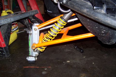 2004 Arctic Cat F-7 Firecat - Close-up view of a snowmobile's front suspension system, orange A-arms and a yellow coilover shock.