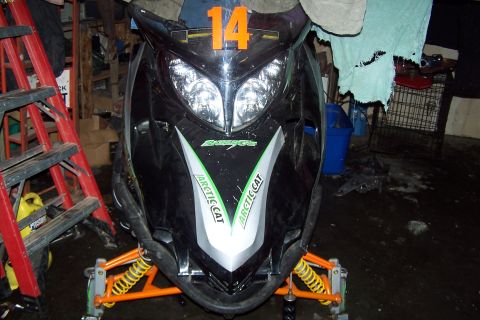 2004 Arctic Cat F-7 Firecat - A black Arctic Cat snowmobile is parked indoors, with a red ladder to the left and various items in the background.