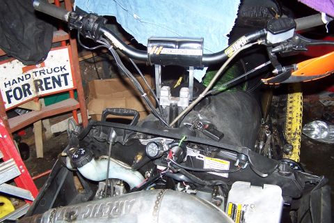 2004 Arctic Cat F-7 Firecat - Close-up view of a snowmobile's engine and handlebars, with a "Hand Truck For Rent" sign visible in the background.