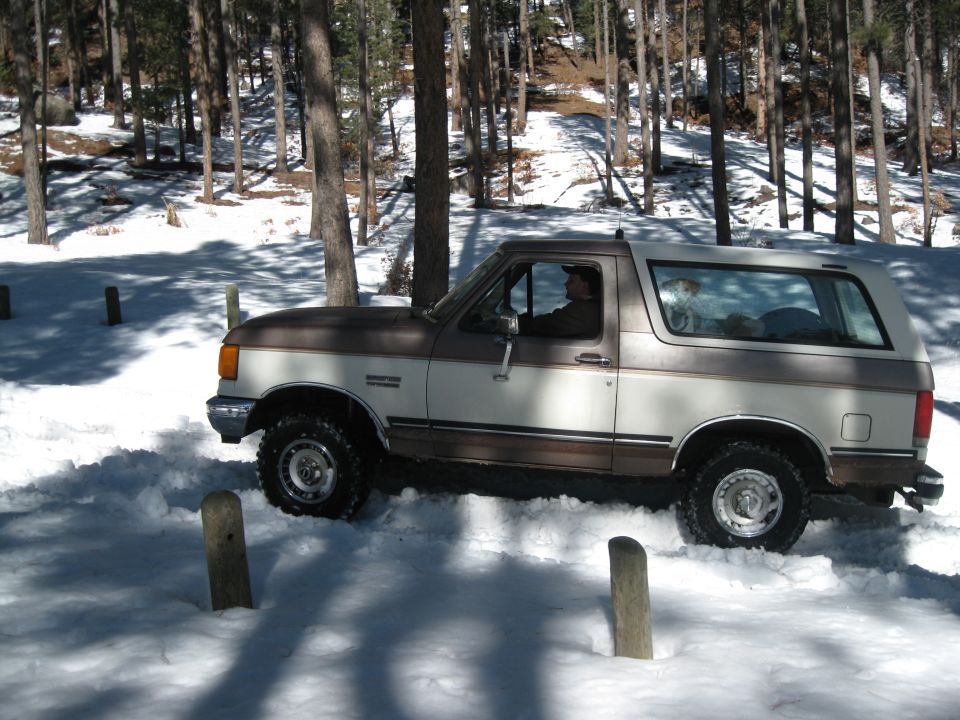 Side view of a 1993 Ford Bronco driving through snow