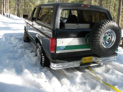 1993 Ford Bronco - Ford Bronco with spare tire is stuck in deep snow on a wooded road.