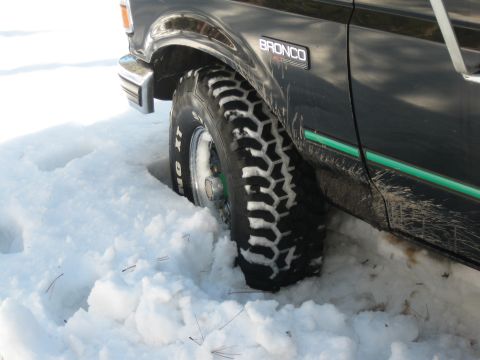 1993 Ford Bronco - A 1993 Ford Bronco navigates through deep snow, with its aggressive tire tread visible.