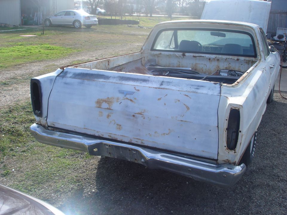 Rear view of a rough faded white project car-based pickup outdoors