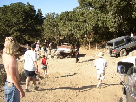 1989 Ford Bronco - People gather around off-road vehicles on a dirt trail during an event.