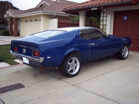 1971 Ford Mustang - A blue 1971 Ford Mustang coupe is parked in front of a house and garage.