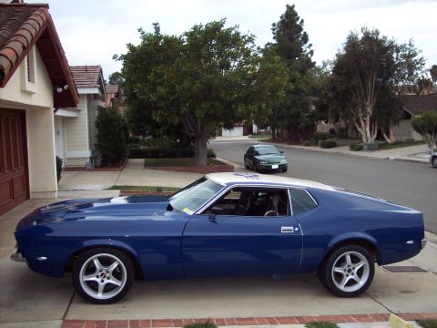 1971 Ford Mustang - A blue 1971 Ford Mustang coupe with a white roof is parked in a driveway.